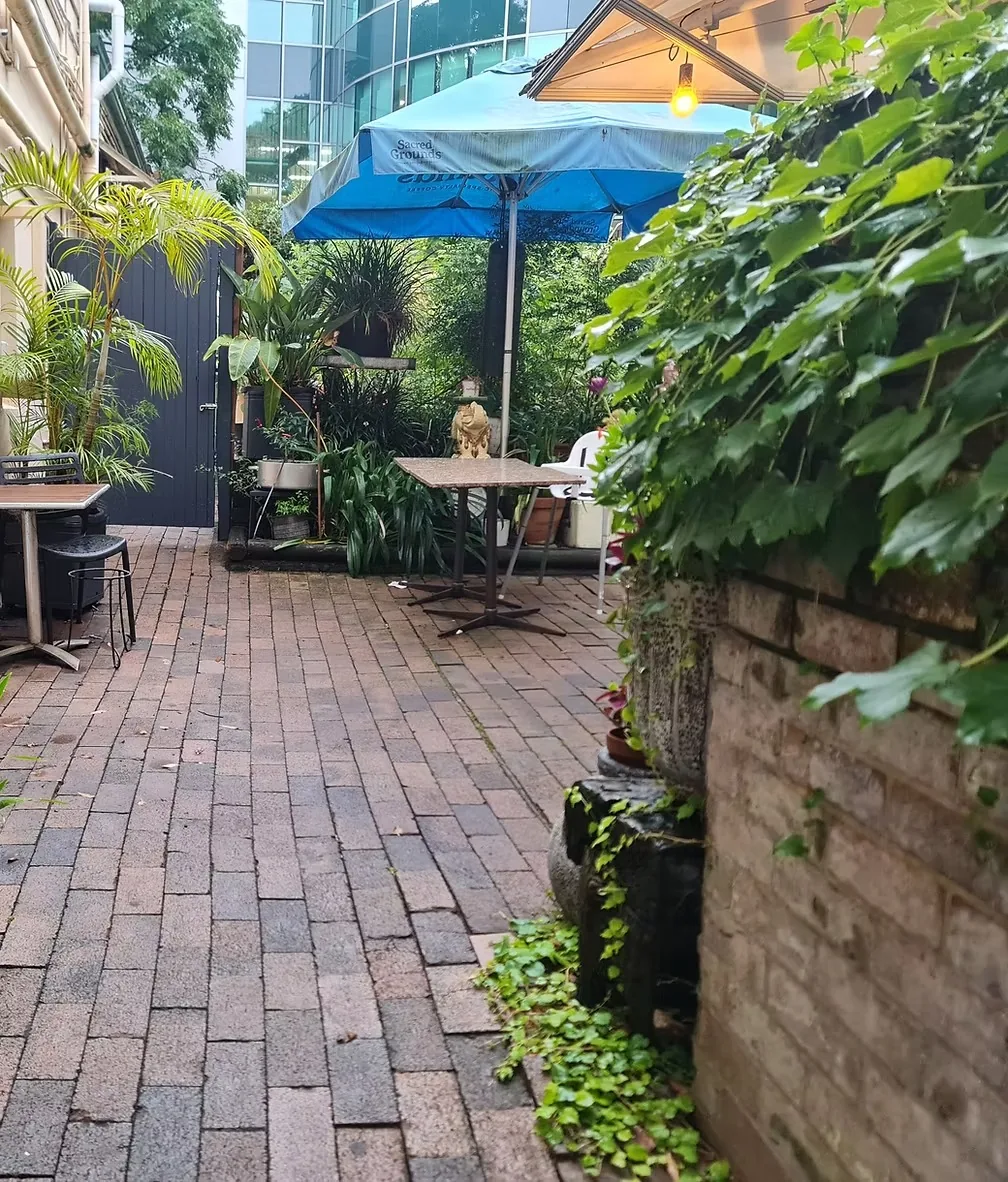 The brick courtyard at Soho on Miller with plants and blue umbrellas