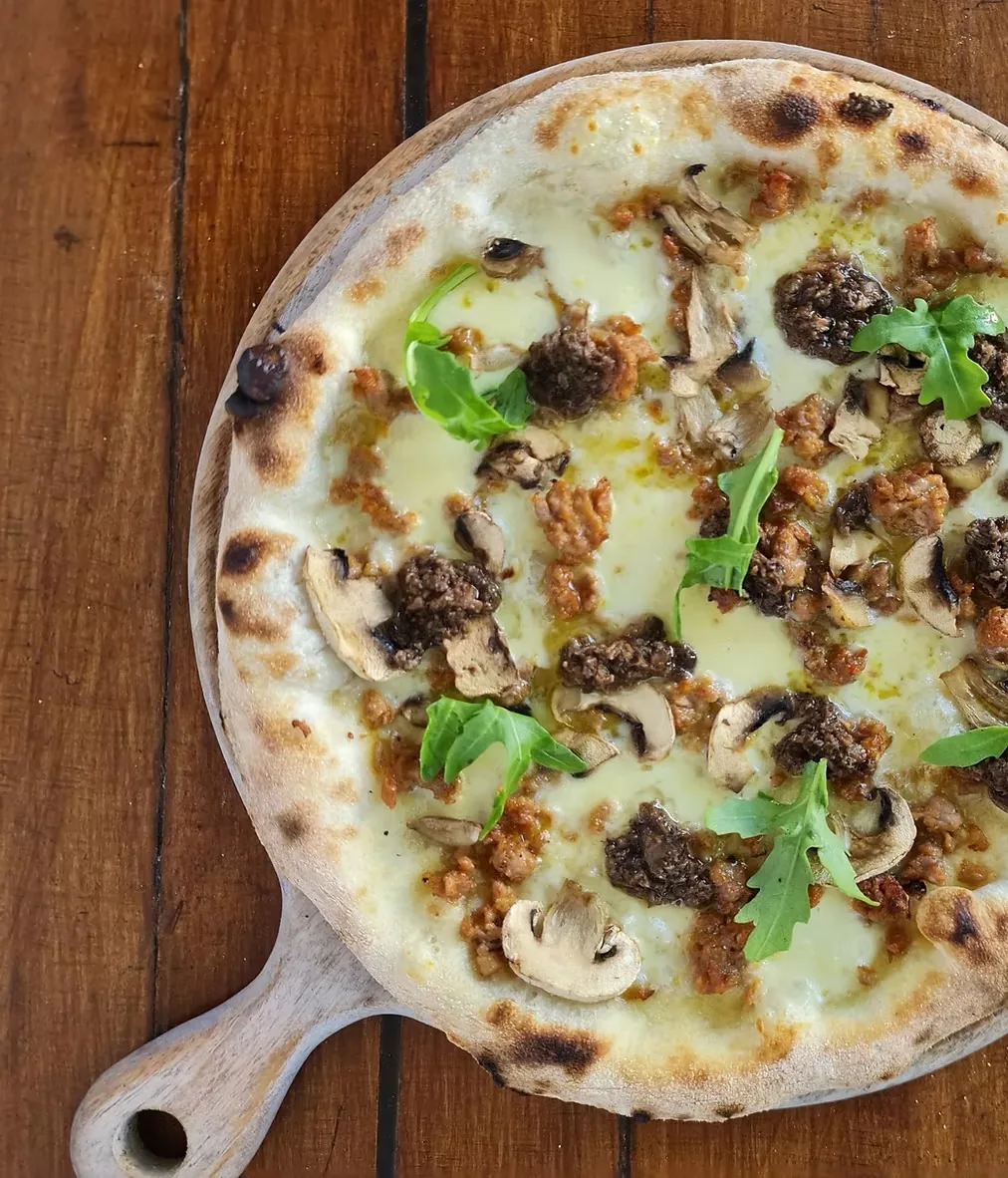 A white pizza with mushrooms on a wooden board